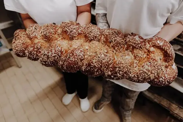 Zwei Bäcker halten einen riesigen Hefezopf